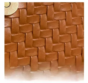 Close-up of brown woven PU leather texture and gold circular metal buckle on the bag