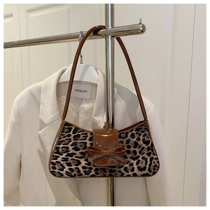 Close-up of leopard print shoulder bag with brown leather bow and slim shoulder strap