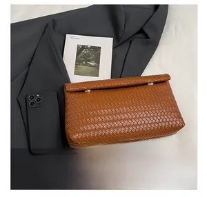 Close-up of brown woven leather clutch showing cross-weave texture and rivet detail