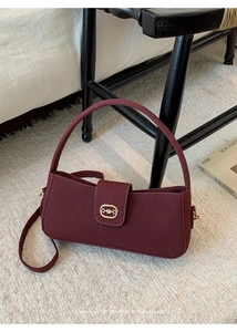 Detailansicht der weinroten matten Ledertasche mit goldener Schnalle auf Teppich
