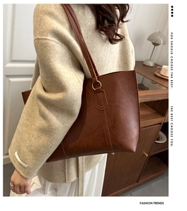 Detailed close-up of large brown tote bag with pebble leather texture worn by a model