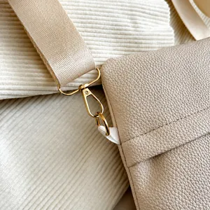 Detail des goldenen Metallhakens an der beigen Crossbody-Tasche mit Lederprägung