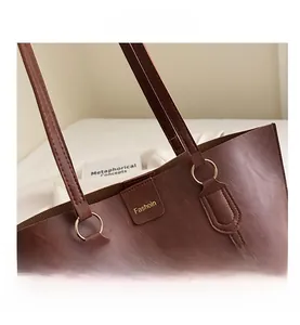 Detail of premium brown tote bag featuring fine leather texture and gold hardware