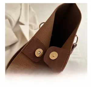 Detail view of the metal magnetic clasp and textured fabric lining of brown tote bag