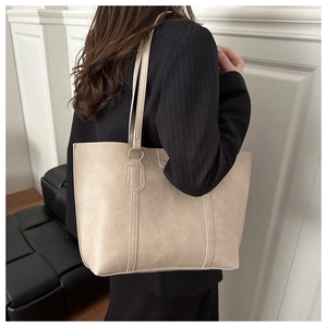 Detailed view of the creamy beige tote bag's vintage leather texture and slim shoulder straps