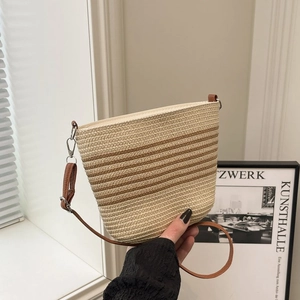 Détail d'un sac seau tissé rayé avec bandoulière en cuir marron au style bohème