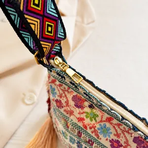 Detailed close-up of smooth gold zipper and colorful woven strap on ethnic canvas bag