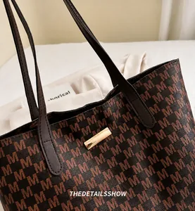 Detail of vintage monogram tote bag with brown leather handles and golden metal plaque