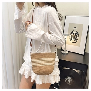 Détail du sac seau tissé à rayures avec bandoulière en cuir marron et décor moderne