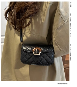 Detailed close-up of a black quilted shoulder bag with a vintage gold and amber clasp