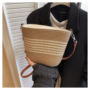 Détail du sac seau tissé à rayures avec bandoulière en cuir marron et fermoir métal