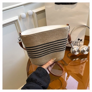 Détail d'un sac seau tressé avec rayures noires et détails de bandoulière en cuir