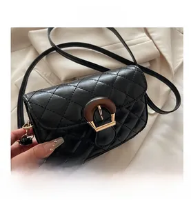 Detail of black quilted leather crossbody bag with vintage wood grain buckle and gold clasp