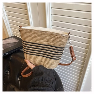 Détails d'un sac seau tissé avec rayures noires et bandoulière en cuir marron