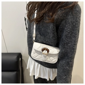 Detailed shot of white quilted shoulder bag with tortoiseshell D-ring buckle