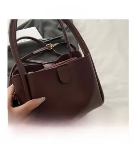 Detail view of burgundy leather tote bag with three compartments and adjustable strap