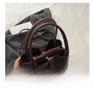 Detailed interior of a deep burgundy tote bag showing triple compartments and a zipper pocket