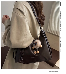 Nahaufnahme einer dunkelbraunen Ledertasche mit Alpaka-Anhänger und Logo-Aufdruck