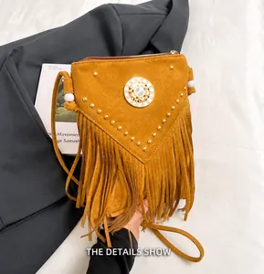Détail de la texture en daim marron avec clous métalliques et franges sur sac bandoulière
