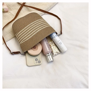 Détail du sac seau tissé à rayures montrant l'espace intérieur avec téléphone et maquillage