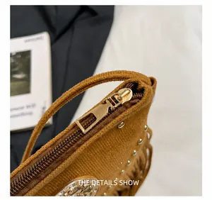 Détail du zip doré et des clous métalliques sur ce sac bandoulière en daim marron
