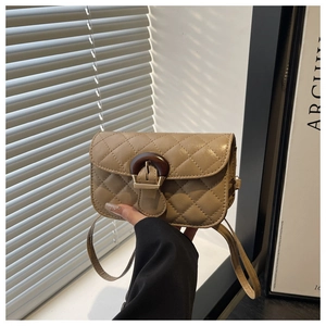 Detail of quilted beige crossbody bag with wooden ring buckle and soft interior lighting