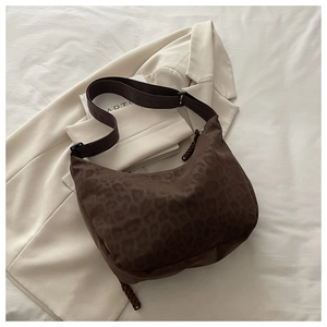 Detail of leopard print half-moon bag with woven tassel and adjustable wide strap