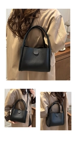 Detail view of a black leather bucket tote bag with round handles and adjustable strap