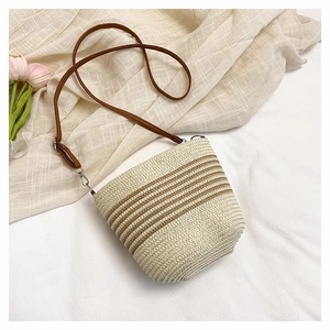 Détail du sac seau tissé avec rayures marron et une bandoulière en cuir de qualité