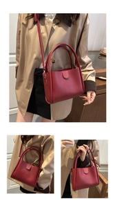 Detail view of wine red bucket bag with dual handles and adjustable shoulder strap