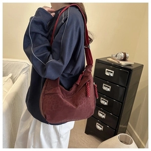 Detail view of burgundy leopard print crossbody bag with wide strap in cozy home setting