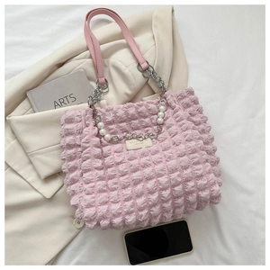 Detail van roze bubbelgeplooide draagtas met parels en zilveren ketting schouderriem