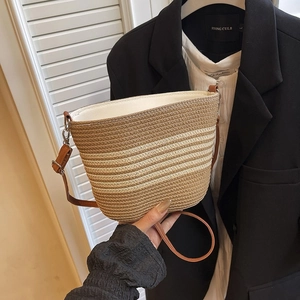 Détail du sac seau tissé avec rayures beiges et bandoulière réglable en cuir marron