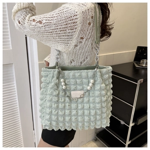 Detail van mintgroene bubble textuur tas met zilveren ketting en parel decor