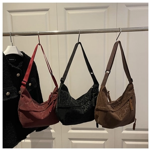 Close-up of three leopard print dumpling bags in red, black, and brown suede finish