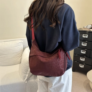 Chic burgundy leopard print crossbody tote bag with wide strap on a model shoulder