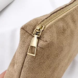 Close-up of golden smooth zipper detail on camel faux suede tote bag with fine texture