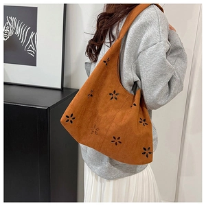 Detail of caramel suede tote bag with laser-cut floral patterns and wide shoulder strap
