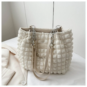 Crèmewitte shopper met bubbeltextuur, parelketting en een rechthoekig lederen label erop