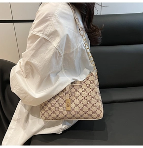 Détail d'un sac porté épaule vintage beige à motif floral rouge et chaîne dorée épaisse