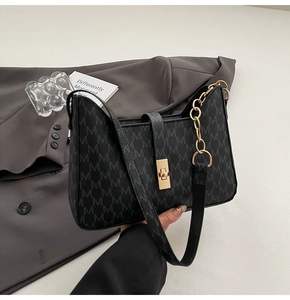 Gros plan du fermoir rotatif doré et du motif monogramme gris sur le sac à bandoulière