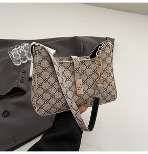 Détail du sac hobo beige avec motifs floraux bruns, chaîne dorée et boucle en métal