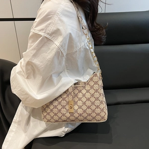 Sac à bandoulière rétro à motif trèfle avec chaîne dorée porté par mannequin sur canapé