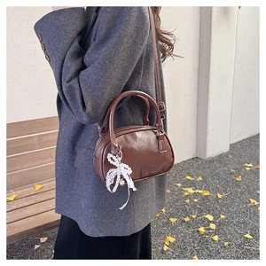 Dark brown leather crossbody bag with pearl bow charm and top handle for women