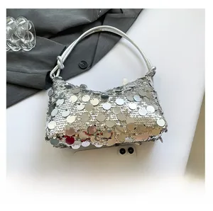 Detail of silver sequin hobo bag showing size comparison with a smartphone for scale
