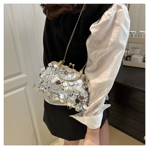 Detail einer silbernen Pailletten-Schalentasche mit Goldkette an einem Model