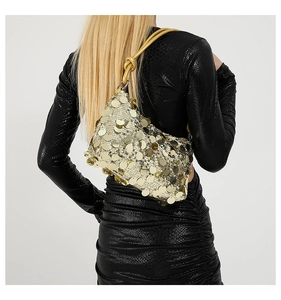 Detail of gold sequin shoulder bag with yellow knotted strap on model in black dress