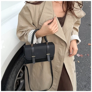 Détail d'un sac à main noir en simili cuir avec texture gaufrée et boucles en métal doré
