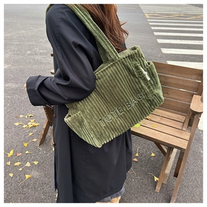 Detail der dunkelgrünen Cord-Tragetasche mit TOTE BAG Stickerei und strukturierter Optik