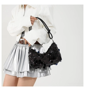 Close-up of black sequined handbag with metallic luster and elegant knot strap detail